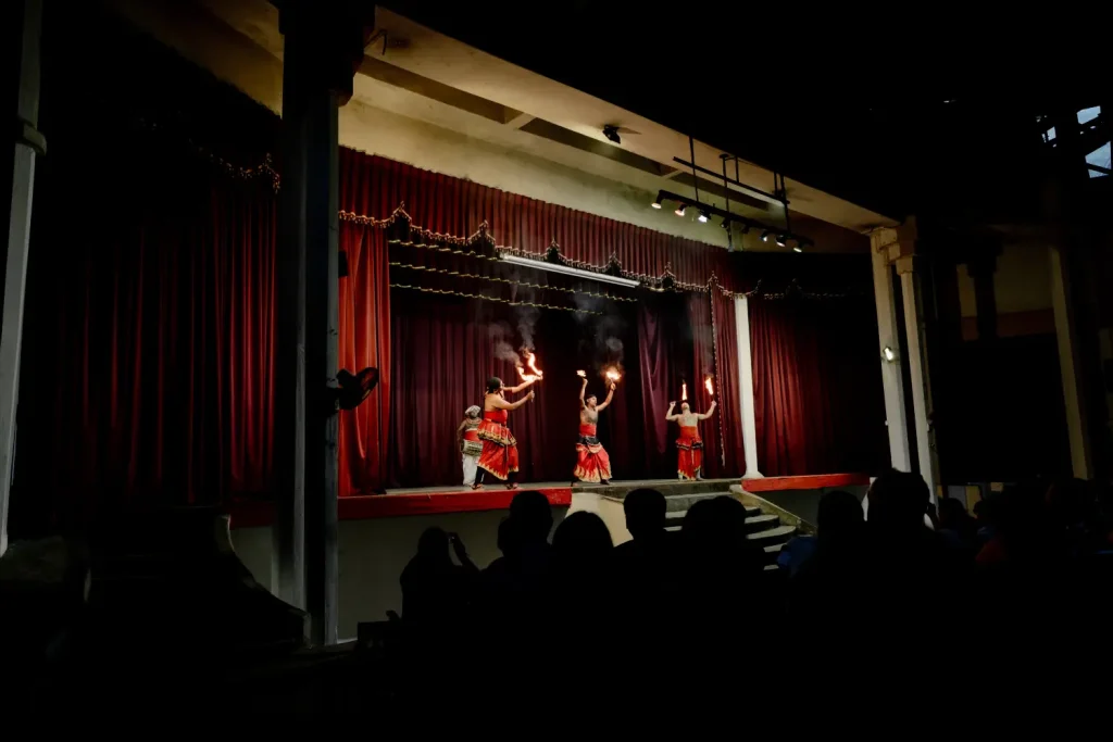 sri lankan traditional dancers performing with torches on a stage.