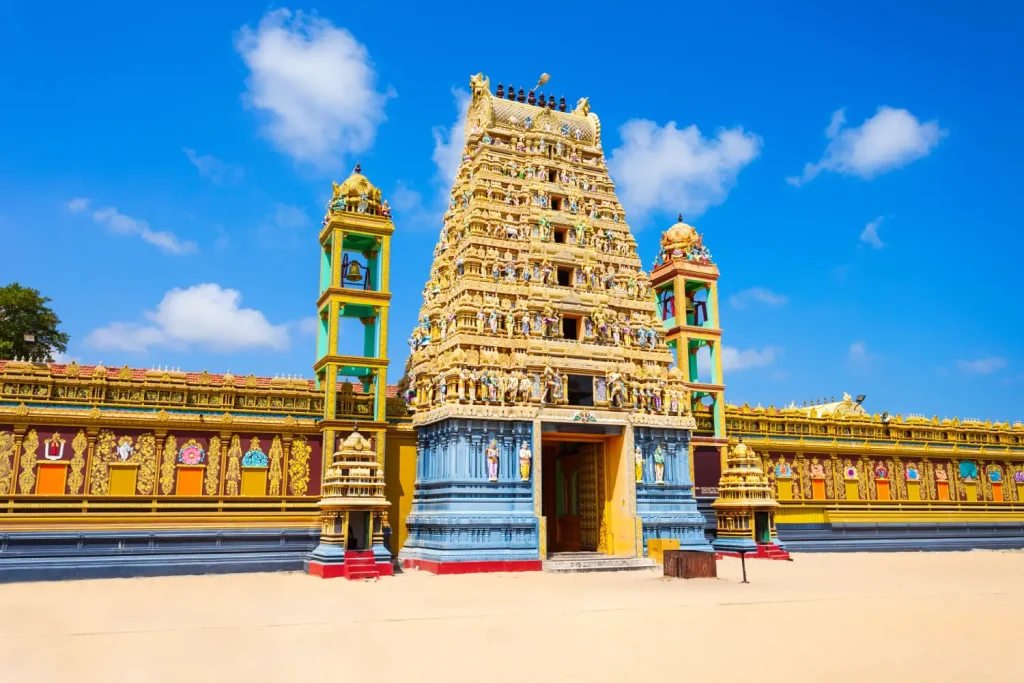 ornate hindu temple with a yellow gopuram and colorful surrounding walls.