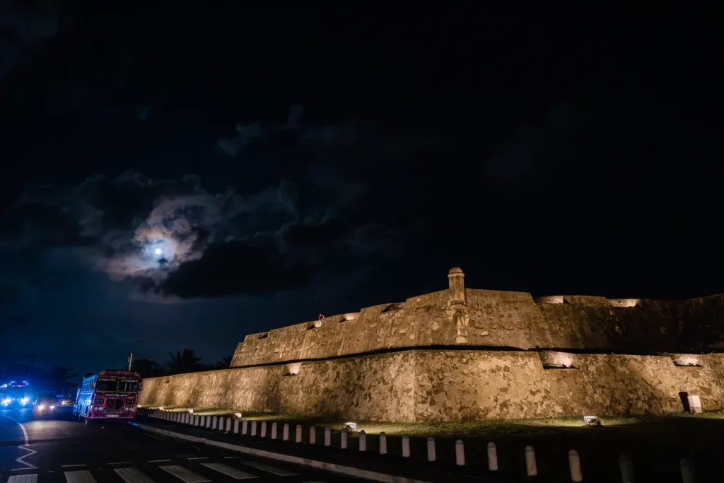 night view of galle fort walls with a full moon and a bus driving