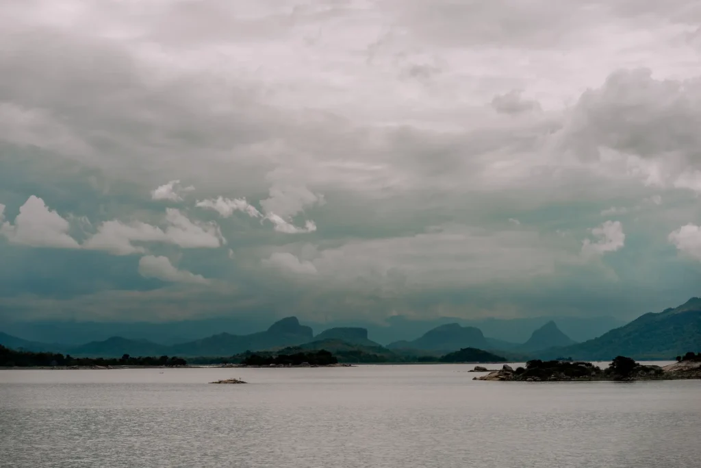 gal oya National Park lake with misty mountains and cloudy sky.